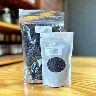 Two packages of freeze-dried elderberry on a wooden surface with a blurred background