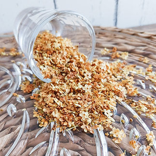 Glass container with spilled dried flowers on a woven surface