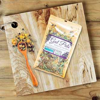 Gal Pals Botanicals package on a wooden cutting board with a spoon and dried herbs.