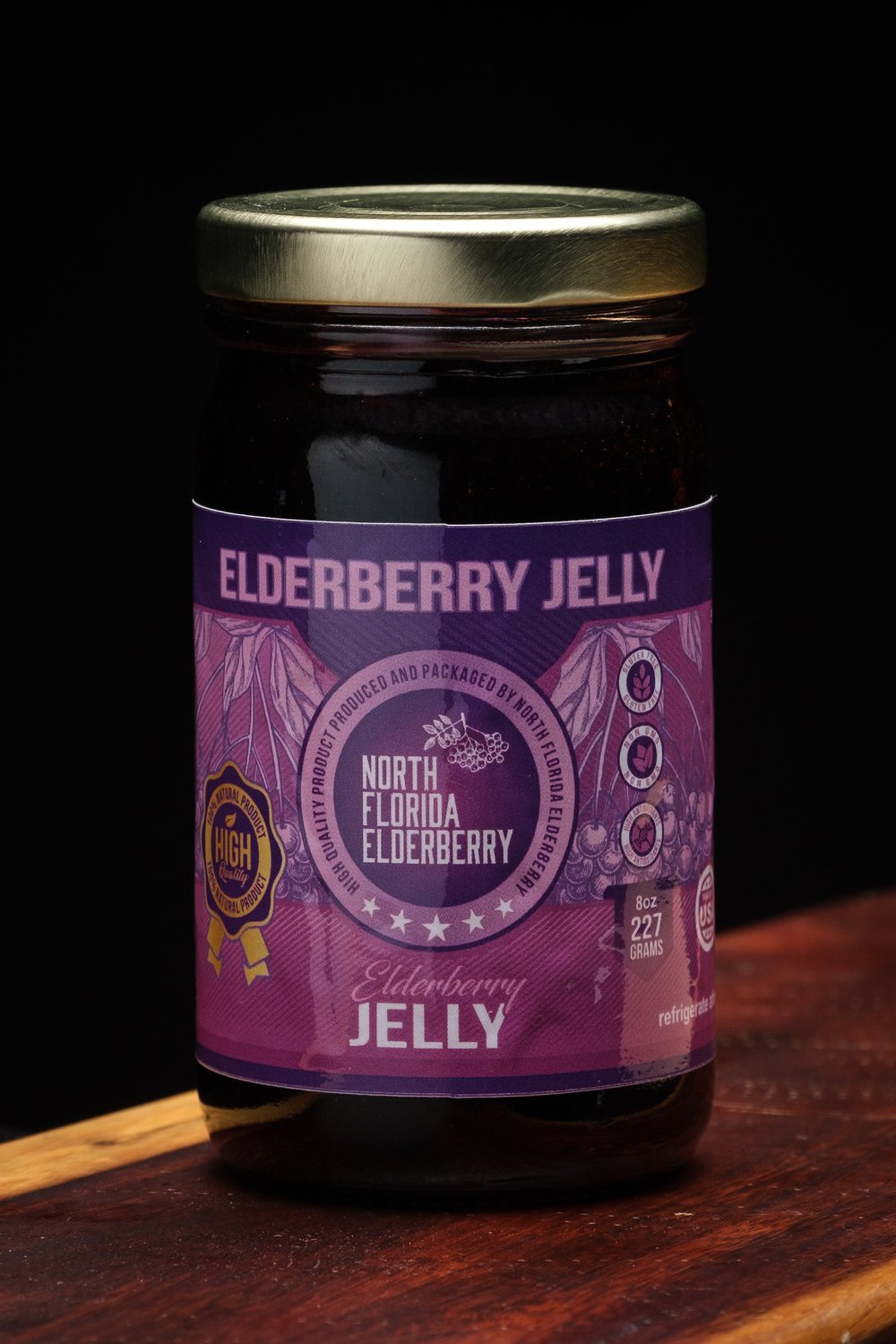 Jar of elderberry jelly with a purple label on a wooden surface
