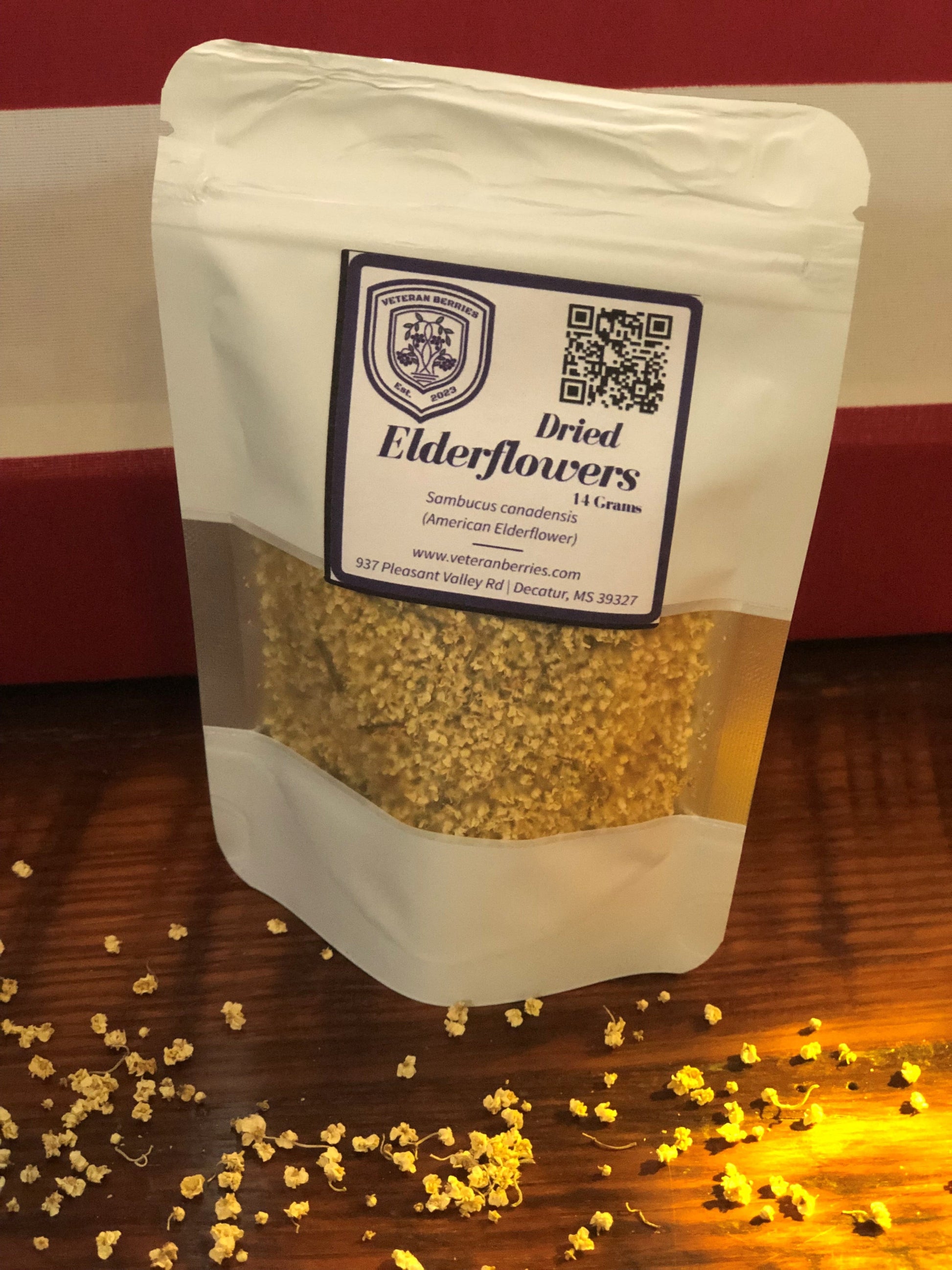 Package of dried elderflowers with a label on a wooden surface with US Flag as backdrop.